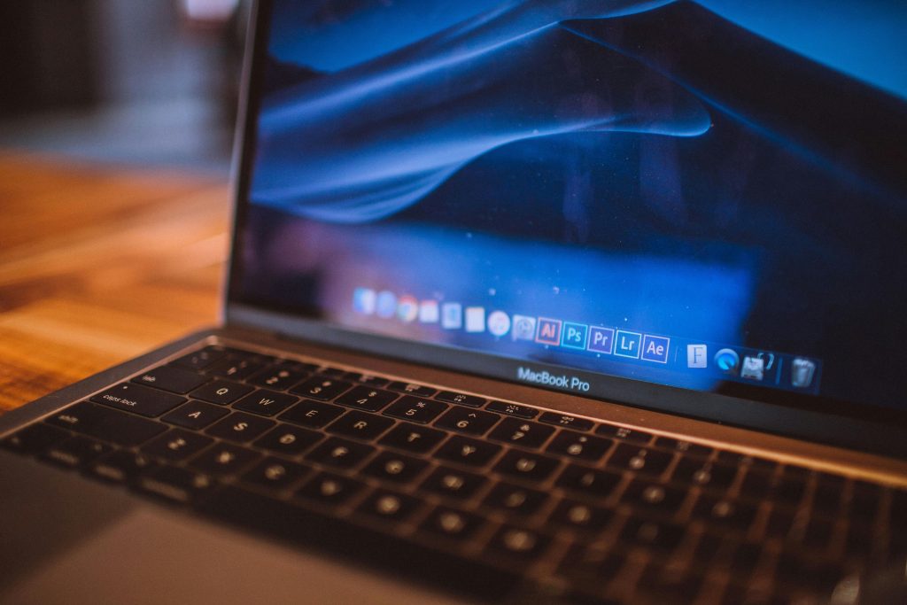 Close-up view of an open MacBook Pro with a dim blue screen in a cozy indoor setting.